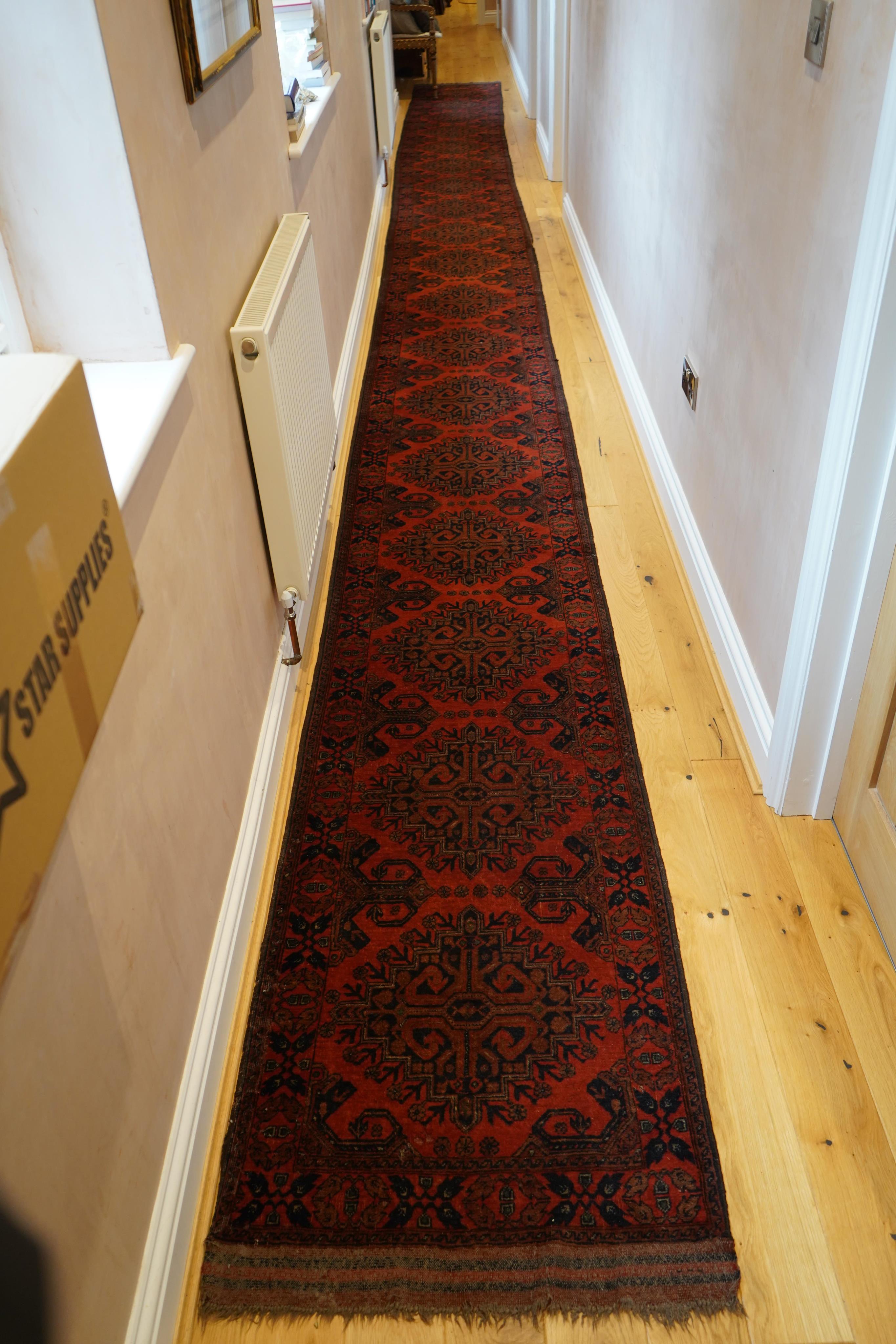 A large Pakistani Bokhara motif hand-knotted wool red ground runner, approx. 950 x 72cm. Condition - fair to good